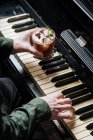 From above of faceless man playing piano with one and and holding glass with cocktail i other hand — Stock Photo