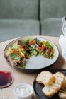 Верхний вид на вкусный салат с вареными сушеными помидорами осьминога элегантный декорированный с зеленью на полу тарелки и подается с жареным хлебом — стоковое фото