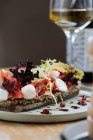 Вкусный ржаной хлеб с соусом и подается с ломтиками помидоров красочный салат и сыр на столе с бокалом вина в ресторане — стоковое фото