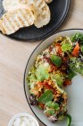 Vue de dessus de salade savoureuse avec poulpe bouilli tomates séchées élégant décoré de verdure sur une demi-assiette et servi avec du pain rôti — Photo de stock