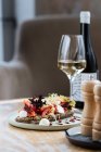 Вкусный ржаной хлеб с соусом и подается с ломтиками помидоров красочный салат и сыр на столе с бокалом вина в ресторане — стоковое фото