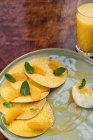 Зверху тарілки з млинцями, прикрашеними скибочками мандаринового листя м'яти, що подається з соусом та склянкою апельсинового соку — стокове фото