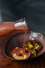 Von oben eine stilvolle Keramikschüssel mit gerösteten Kartoffelscheiben und zartem Schnitzel mit roter Sauce aus dem Glas im Restaurant — Stockfoto