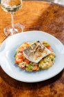From above of fillet fish with small square slices of peppers on plate in restaurant — Stock Photo