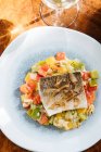De arriba del filete el pez con los trozos pequeños cuadrados de los pimientos en el plato en el restaurante - foto de stock