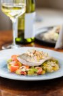 Von oben Filetfisch mit kleinen quadratischen Paprikascheiben auf dem Teller im Restaurant — Stockfoto