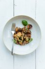 Plato vegetariano de alta cocina con batatas decoradas con hojas de albahaca fresca en la mesa de madera de withe - foto de stock