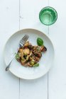 D'en haut plat végétarien de haute cuisine avec des patates douces décorées avec des feuilles de basilic frais sur withe table en bois — Photo de stock