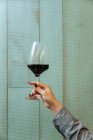 De baixo da mão feminina de colheita com vidro elegante de vinho tinto com interior moderno de restaurante — Fotografia de Stock