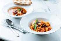 Von oben schmackhafte Pasta mit frischen Tomatenstücken und Auberginen dekoriert mit Basilikumblättern und Soße im Restaurant — Stockfoto