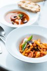 Dall'alto di pasta saporita con pezzi freschi di pomodoro e melanzane decorate con foglie di basilico e salsa in ristorante — Foto stock