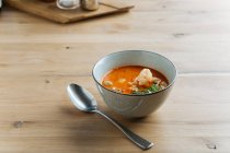 Сверху пряный суп деликатес с креветками и зеленью в керамической миске на столе с металлической ложкой — стоковое фото