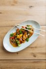 Vue de dessus de tranches de légumes colorés et de viande sur assiette ovale avec baguettes en bois — Photo de stock