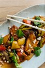 Vista dall'alto di fette di verdure colorate e carne su piatto ovale con bacchette di legno — Foto stock