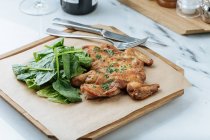 Dall'alto di pollo d'oro fritto ed erbe su asse di legno con foglie di basilico in ristorante — Foto stock