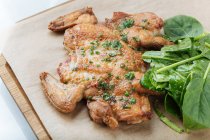 Du dessus du poulet doré frit et des herbes sur une planche de bois avec des feuilles de basilic au restaurant — Photo de stock