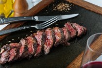 Vista dall'alto di bistecca di fette medie rare sul tavolo con forchetta e coltello nel ristorante — Foto stock