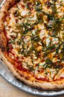 De cima de pizza vegetariana assada suculenta servida com queijo, sementes e ervas na mesa no restaurante — Fotografia de Stock