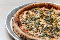 De haut de pizza végétarienne au four juteuse servie avec du fromage, des graines et des herbes sur la table dans le restaurant — Photo de stock