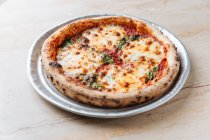 Von oben saftig gebackene Pizza serviert mit Käse und Kräutern auf dem Tisch im Restaurant — Stockfoto