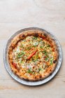 Vista superior de pizza redonda con salsa de tomate y queso derretido adornado con pimiento verde picado y pimienta de cayena sola - foto de stock