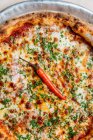Draufsicht auf runde Pizza mit Tomatensauce und geschmolzenem Käse garniert mit gehacktem grünem und einzigartigem Cayennepfeffer — Stockfoto