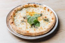 Dall'alto di pizza al forno succosa servita con formaggio ed erbe di basilico sul tavolo nel ristorante — Foto stock