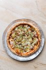 Vista dall'alto della pizza rotonda con mozzarella fusa condita con fette rossastre e cipolla con sottaceti — Foto stock