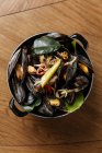 Draufsicht auf schwarzes Weichtiergericht mit verschiedenen gedämpften Gemüsesorten in schwarzem Topf auf dem Tisch — Stockfoto