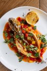 Von oben von ganz gebratenem Weißfisch geschnitten und mit Tomatensauce und Gemüse gefüllt, garniert mit grünem Koriander — Stockfoto