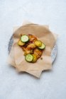 Vista dall'alto della salsa dorata sul piatto con carta da forno decorata con fette di cetrioli freschi verdi e sottaceto sul tavolo — Foto stock