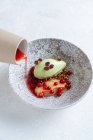 From above of stylish bowl with slice of red fish and avocado served with red berries and pouring with red sauce — Stock Photo
