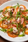 Vue de dessus de tranches rondes fraîches de tomates sur assiette blanche décorée d'herbes vertes et de noix — Photo de stock