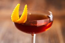 De dessus de cocktail avec du gin de liqueur de vermouth rouge dans un verre élégant décoré de zeste d'orange sur fond flou — Photo de stock