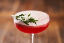 From above of stylish glass with alcohol red cocktail consist of gin egg whites lime juice and raspberry syrup decorated with rosemary — Stock Photo