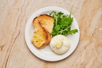 Top view of roasted slices of bread with green arugula and stuffed white dough on white plate in restaurant — Stock Photo