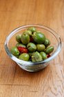 From above of glass bowl with fresh green olives and tomatoes on wooden table in restaurant — Stock Photo