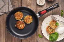 Top view of roasted cutlets in pan on wooden table with stylish served cutlets on plate with basil leaf and mozzarella — Stock Photo