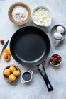 Top view of assorted fresh ingredients for delicious dessert preparation placed around empty frying pan on table in kitchen — Stock Photo