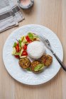 Blick auf den weißen Teller mit veganen Schnitzeln mit weißem Reis und frischem Gemüsesalat auf Holztisch — Stockfoto