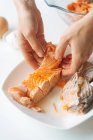 Cortar las manos de la hembra separando trozo de salmón cocido de los huesos mientras se prepara la cena en casa - foto de stock