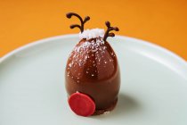 Nahaufnahme Hirschkopf geformtes Dessert für Weihnachtsfeier auf Teller vor orangefarbenem Hintergrund gelegt — Stockfoto