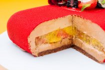 Крупный план вкусный вырезанный торт со сладкими фруктами и красной глазурью помещен на тарелку — стоковое фото