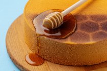 Honey spoon on honeycomb cake — Stock Photo