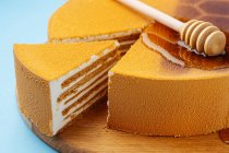 Honey spoon on honeycomb cake — Stock Photo