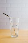 Shiny steel eco friendly sustainable straw in empty glass on wooden table — Stock Photo