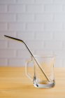 Shiny steel eco friendly sustainable straw in empty glass on wooden table — Stock Photo