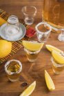 Vue du dessus des verres de tequila dorée avec bord salé et tranches de citron sur la table en bois — Photo de stock