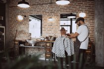 Visão traseira do homem ruiva irreconhecível no barbeiro cabeleireiro moderno cortando seu cabelo — Fotografia de Stock
