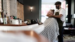 Barber doing face massage to handsome redhead man with sitting in chair — Stock Photo